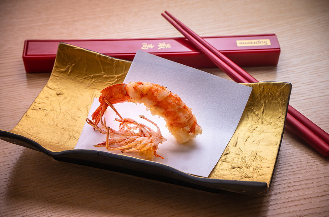 Prawn sushi on gold leaf with red chopsticks, Curate Group