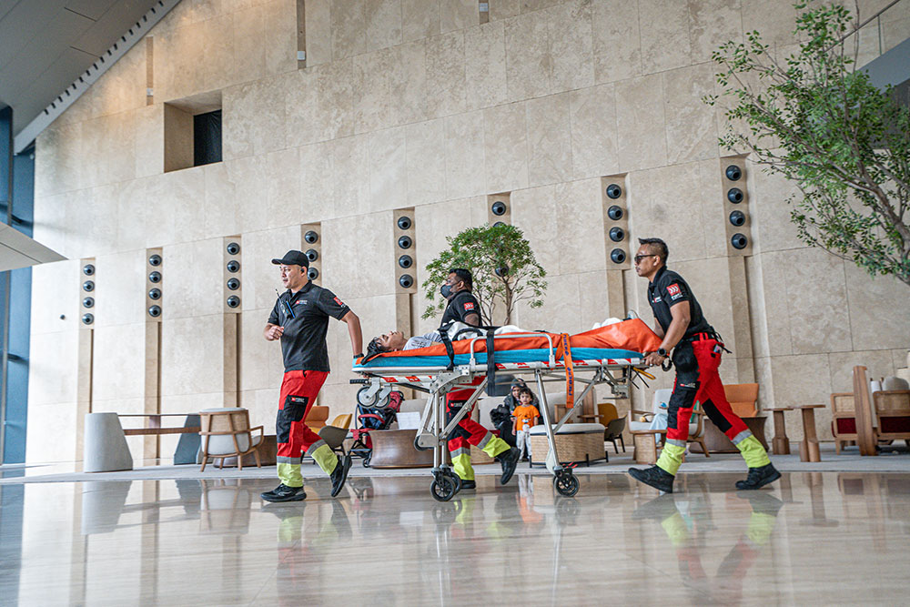 A medical team wheels a patient on a stretcher across the lobby of Menara Merdeka Maybank during the IHH Sky Race medical drill
